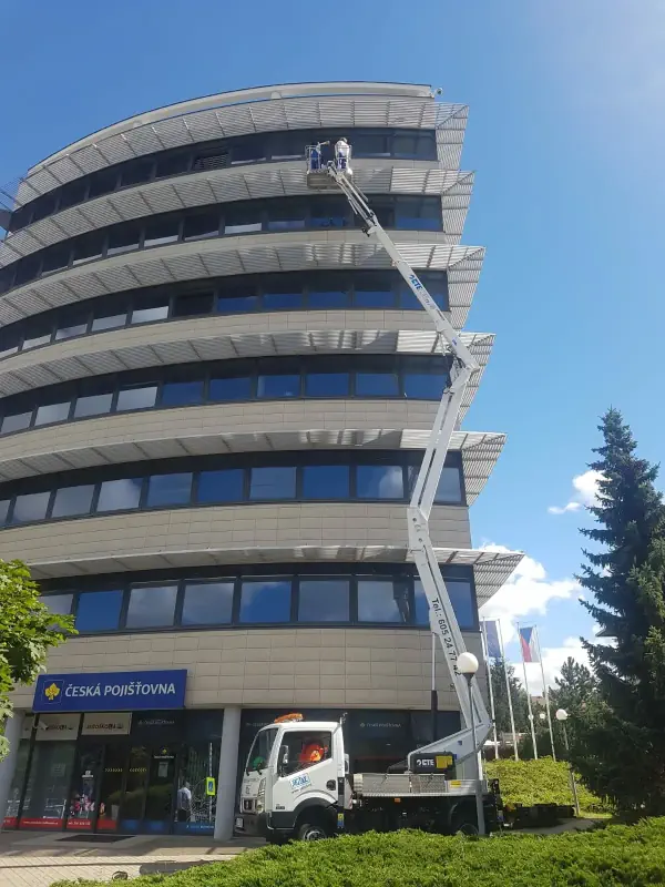 Muž čistí okna vysoké budovy z plošiny